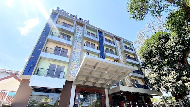 A multi-story hotel with a modern facade, a staircase leading to the entrance, and a sign for a nearby cafe. - Kyriad Haka Makassar (Makassar)