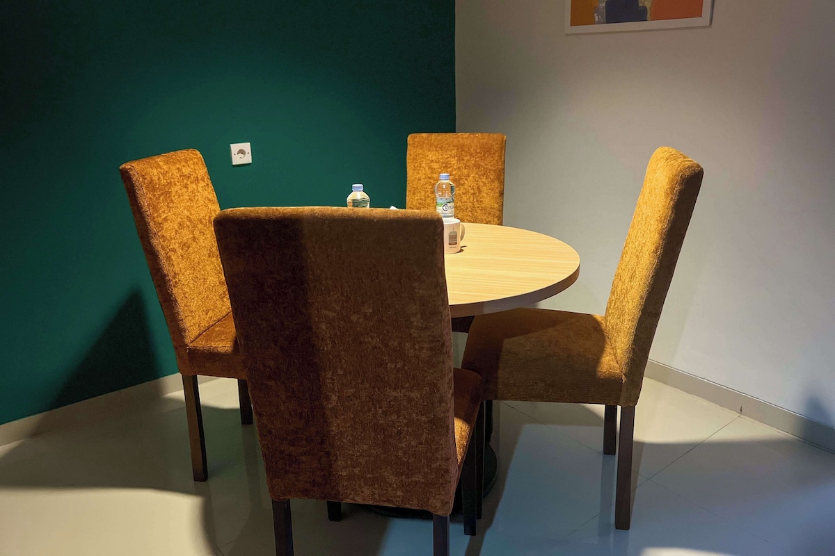 A conference room with a round table and four chairs, two water bottles on the table, and a map on the wall.