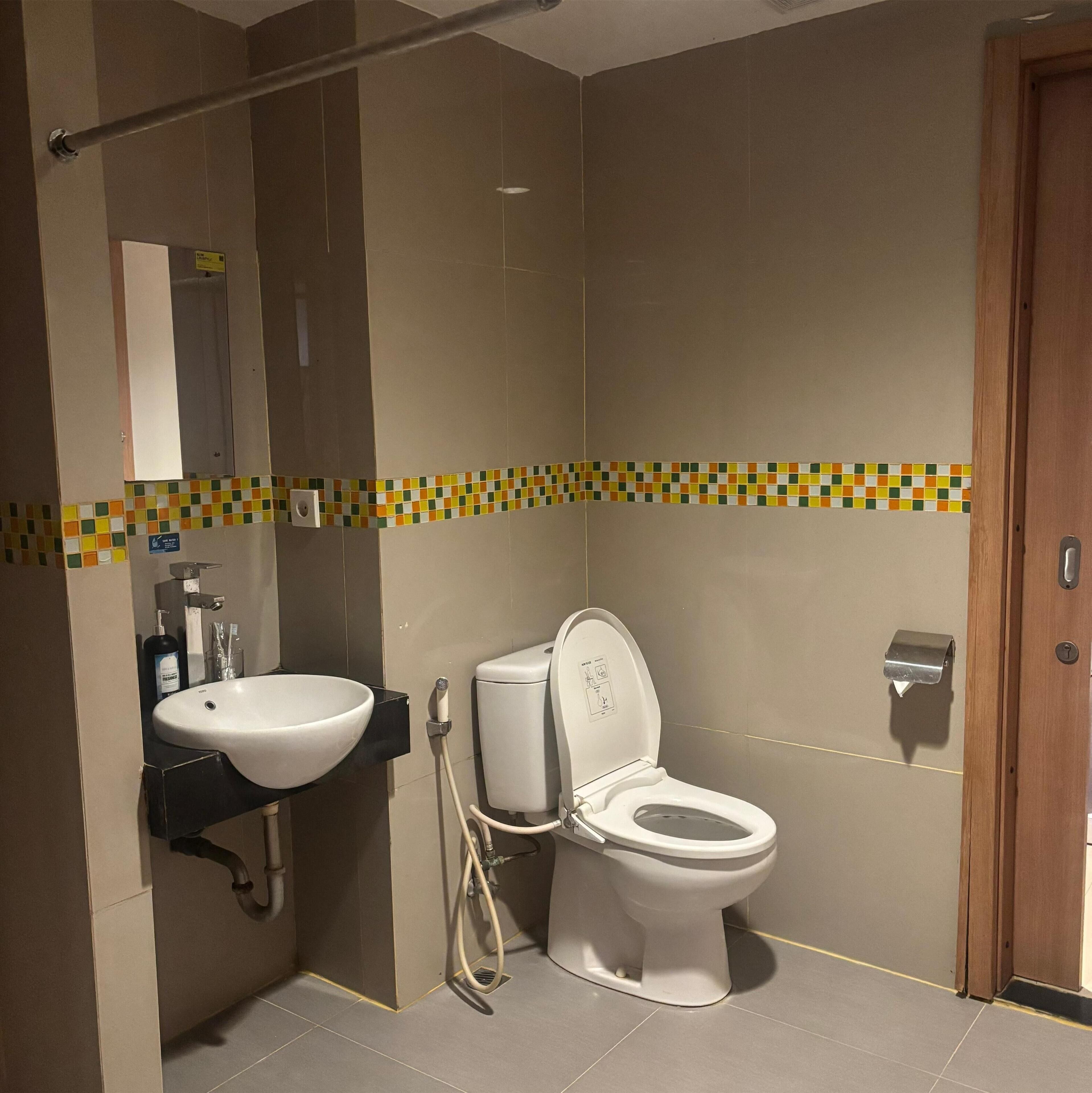Et moderne badeværelse med en hvid vask, toilet og et spejl over vasken.