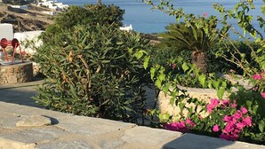 A stone wall with a view of the sea and distant hills. - Cozy apartment for 2 near Ornos with sea and sunset view  (Ornos Mykonos)