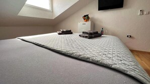 A neatly made bed with a quilted cover, a small bedside table with a fruit bowl, and a TV mounted on the wall. - Room in Zaton (Zadar) with Seaview, Terrace, WIFI, Washing machine (4141-7) (Nin)
