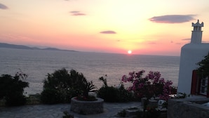 Une terrasse dallée de pierres, offrant une vue sur la mer au coucher du soleil.