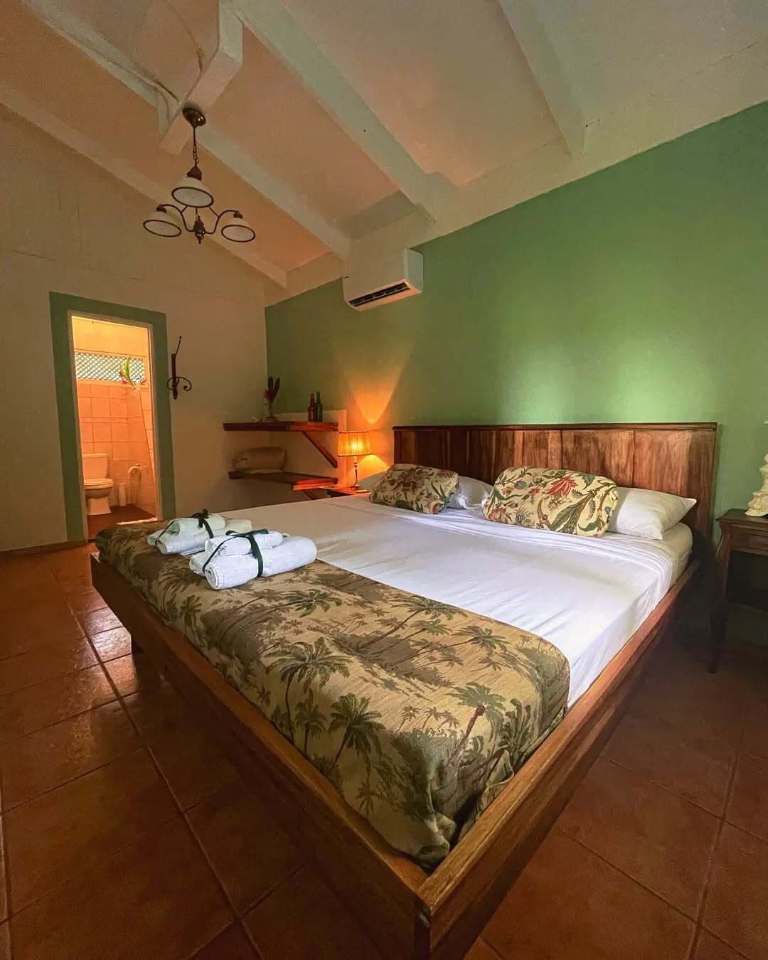 Ein Schlafzimmer mit einem großen Bett, einem hölzernen Kopfteil, einem Nachttisch, einer Lampe und einer Pendelleuchte.