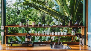 A kitchen with wooden shelves holding various kitchenware and a gas stove. - Colina Secreta - Glamping and Villas (Cahuita)