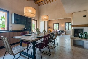 Una cocina amplia con electrodomésticos modernos, un comedor con una mesa grande y sillas, y una sala de estar acogedora con chimenea.