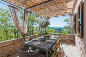 Un área de comedor al aire libre con una mesa para cuatro, con vistas a un paisaje pintoresco.