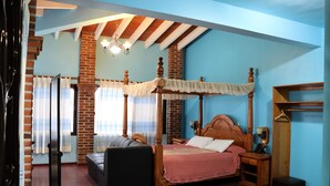 A four-poster bed with a canopy, a sofa, a small table, and a nightstand in a room with brick walls and wooden beams. - Hotel Zaragoza Tepoztlan (Tepoztlán)