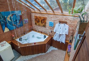 Un baño con bañera de madera, cabina de ducha de vidrio y pared de ladrillo.