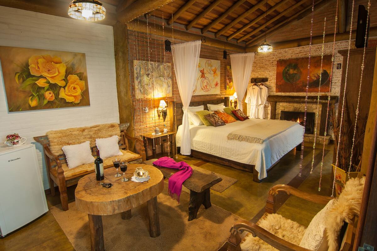 A cozy room with a bed, a wooden table, and a fireplace.