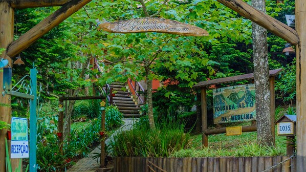 A rustic wooden staircase leading to a sign that reads "Aventura Tranquilidade." - Pousada Alto da Neblina (Camanducaia)