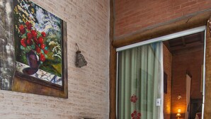 A spa area with a hot tub, decorative pillows, a painting, and a room entrance. - Pousada Alto da Neblina (Camanducaia)