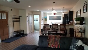 A living room with a sofa, a dining table with chairs, a ceiling fan, and a kitchen area in the background. - Big Sky Haven, Quiet and Centrally Located for Skiing, Fishing, Golfing 
 (Big Sky)