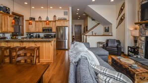 A modern kitchen with wooden cabinets, a stainless steel refrigerator, and pendant lighting. - Eagle's Rest (McHenry)