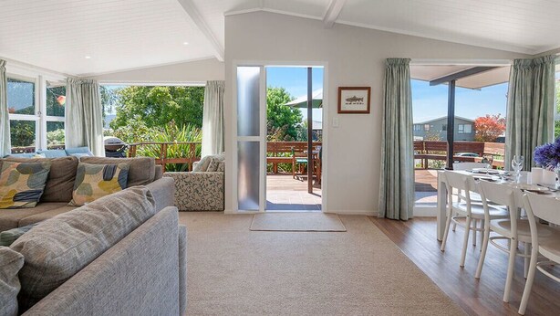 A spacious living room with a large sofa, a dining table, and a view of the outdoors.