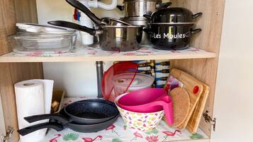 Un meuble de cuisine contenant des casseroles, des poêles et une planche à découper.