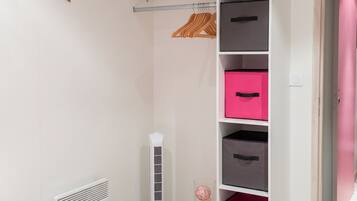 A bedroom with a bed, a wardrobe with drawers, a radiator, a heater, and a closet with a pink door.