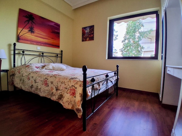 A bedroom with a bed, a window, and two wall art pieces.