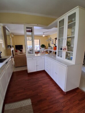 A compact kitchen with white cabinetry, a built-in oven, and a dining area with a sofa.