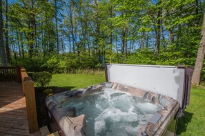 A hot tub on a wooden deck surrounded by lush greenery and trees. - Johnny Appleseed (Oakland)
