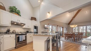 Una cocina amplia con armarios blancos, una isla grande y un comedor con sillas de madera.