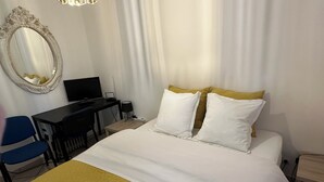 A hotel room with a bed, a desk with a computer, a chair, and a mirror. - Paradis la Provence entre Vienne et Lyon (Saint-Cyr-sur-le-Rhône)