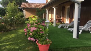 A house with a patio, a lawn, and a flower bed with pink flowers. - Paradis la Provence entre Vienne et Lyon (Saint-Cyr-sur-le-Rhône)