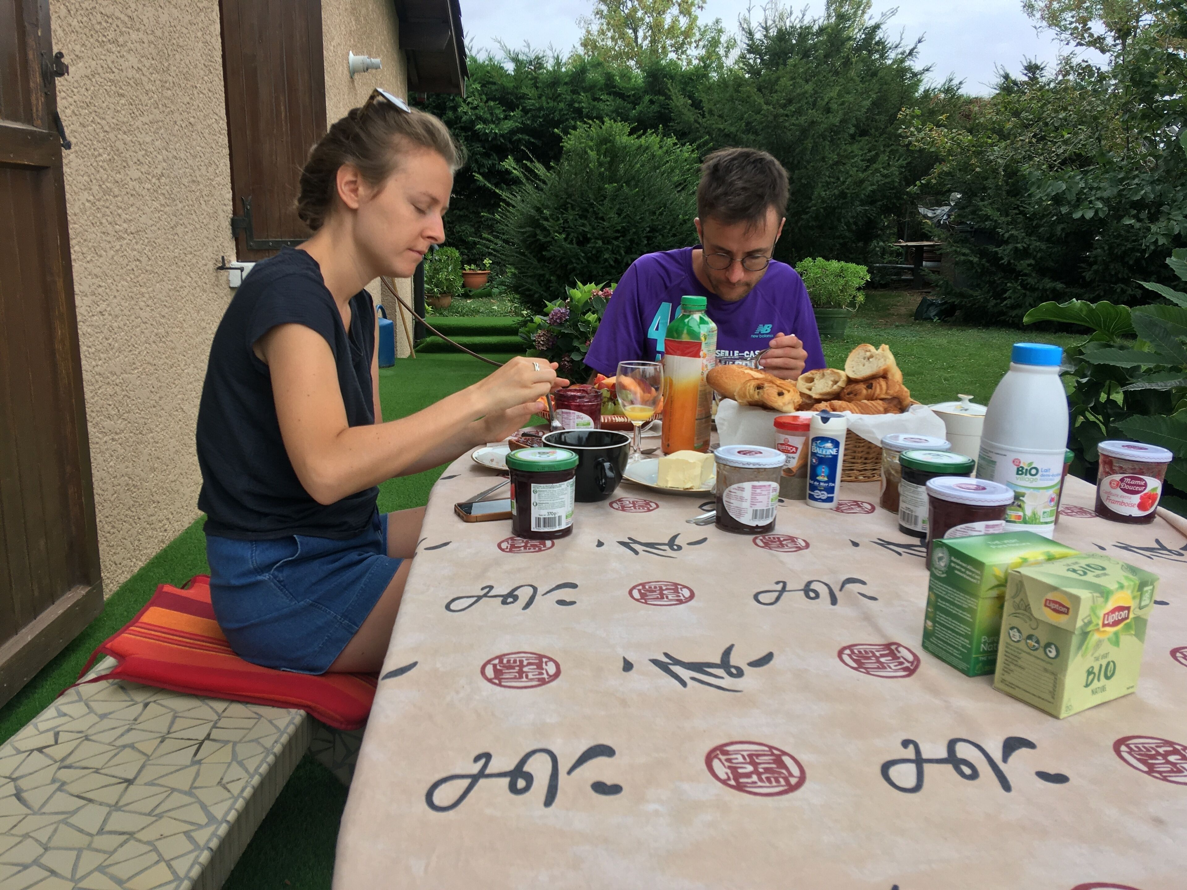 Duas pessoas jantando em uma mesa ao ar livre, com diversos pratos e bebidas.