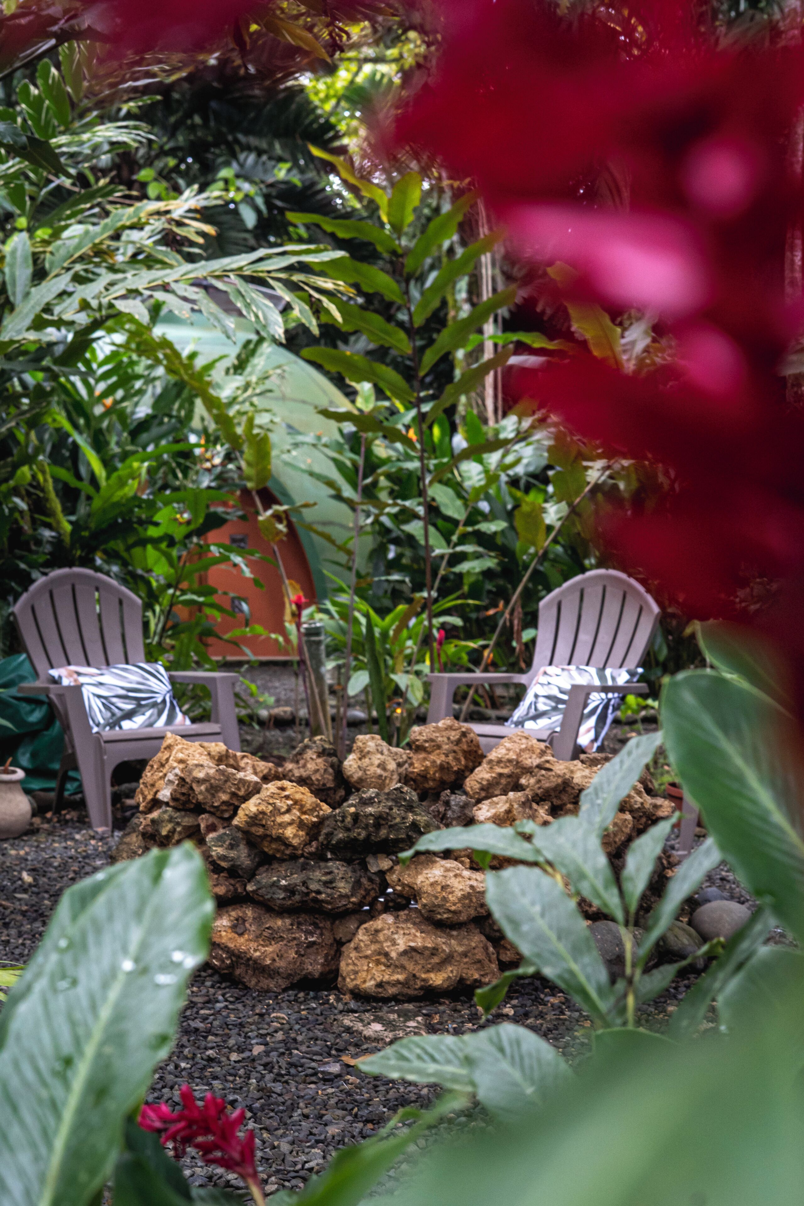 Un jardín con dos sillas Adirondack, un muro de rocas y diversas plantas.