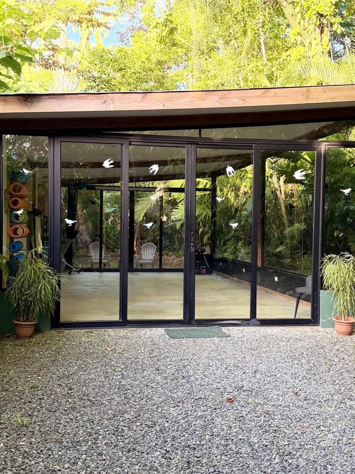 A modern building with large glass doors and a gravel ground.