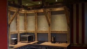 A rustic kitchen with wooden beams, a microwave, a toaster, and a coffee maker on a wooden countertop. - Mycologne (Cologne)