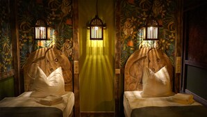A room with two beds, each with a wooden headboard and a white pillow. There is a green curtain in the center, and a wall-mounted light fixture above the curtain. - Mycologne (Cologne)
