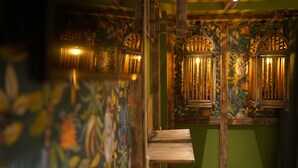 A room with wooden beams, a green wall, and a mural. There are two windows with bars and a bench. - Mycologne (Cologne)