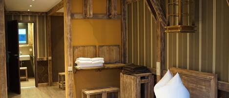 Ein rustikales Zimmer mit einem hölzernen Bett, einer Holzbank und einem kleinen Tisch.
