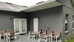 Ulkoterassi, jossa on betonilattia, valkoiset metallituolit ja pöytä.