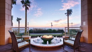A balcony with wicker chairs, a fire feature, and a view of the sunset over the ocean. - Ocean Beach Club - 1BR/1BA - Amazing Oceanfront Views! (Virginia Beach)