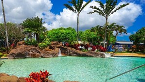 A swimming pool with clear water, surrounded by rocks and tropical plants. - KIAHUNA BEACH HOUSE #50 NEW REMODEL GROUND FLOOR NEW AC TWIN BRIDGES GARDEN VIEW (Koloa)