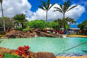 A swimming pool with clear water, surrounded by rocks and tropical plants. - KIAHUNA BEACH HOUSE #50 NEW REMODEL GROUND FLOOR NEW AC TWIN BRIDGES GARDEN VIEW (Koloa)
