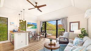 A spacious living area with a kitchen, dining area, and a balcony with a view of the beach. - KIAHUNA BEACH HOUSE #50 NEW REMODEL GROUND FLOOR NEW AC TWIN BRIDGES GARDEN VIEW (Koloa)