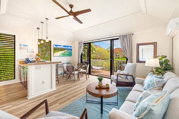 A spacious living area with a kitchen, dining area, and a balcony with a view of the beach. - KIAHUNA BEACH HOUSE #50 NEW REMODEL GROUND FLOOR NEW AC TWIN BRIDGES GARDEN VIEW (Koloa)