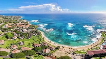 An aerial view of a coastal area with houses, a beach, and the ocean.