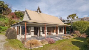 Une maison moderne avec un toit en pente, de grandes fenêtres et une véranda couverte.