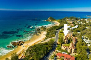 Vista aérea de una zona costera con playa, costa rocosa y edificios residenciales.