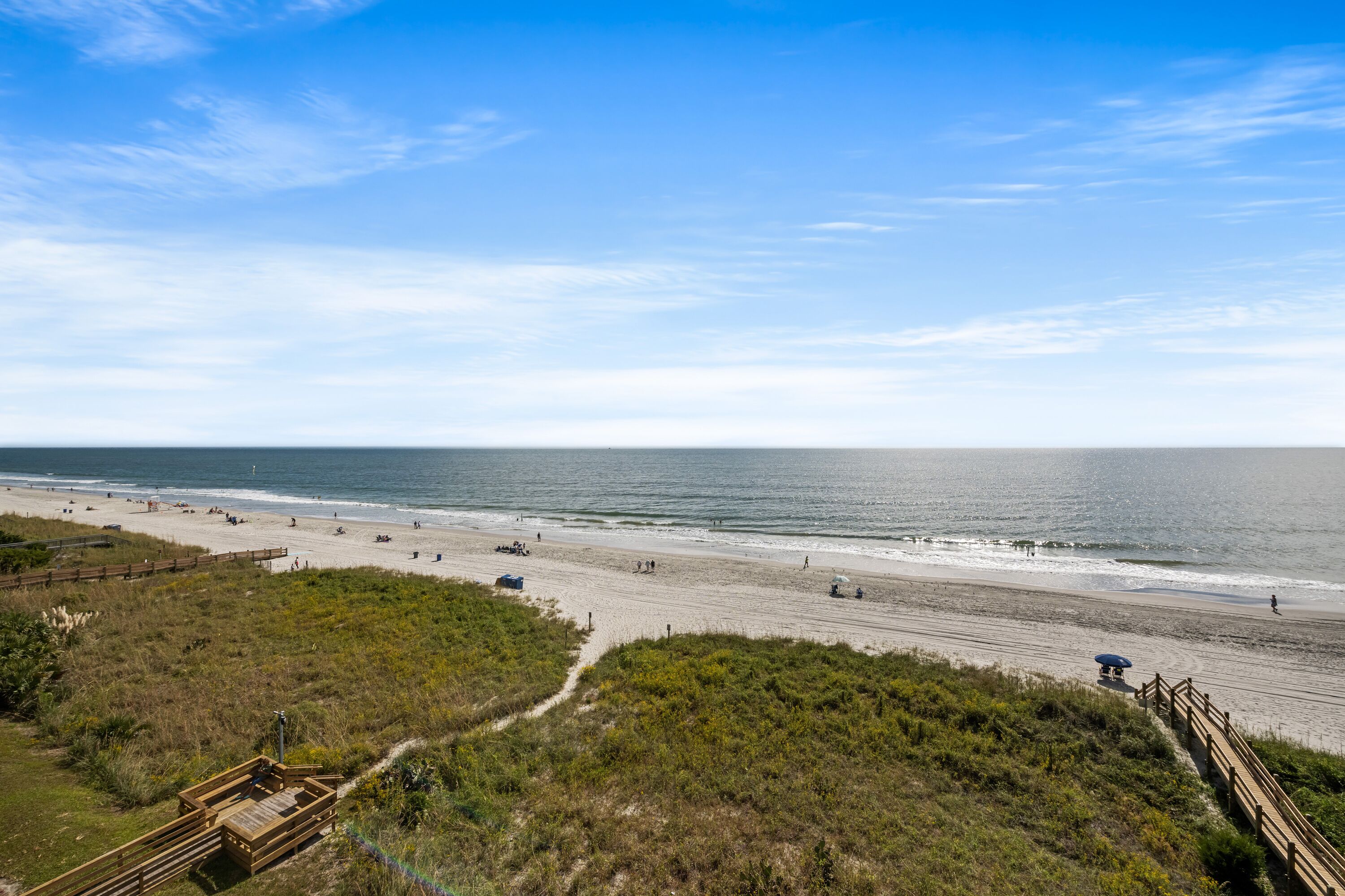 A beach with a wooden boardwalk, sandy beach, and ocean view.