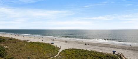 A beach with a wooden boardwalk, sandy beach, and ocean view.