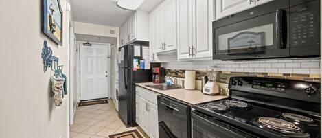 A kitchen with white cabinets, a black microwave, a black stove, and a dishwasher.