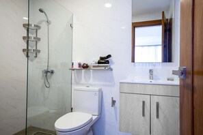 A modern bathroom with a glass-enclosed shower, a toilet, and a vanity with a mirror. - Brilliant Harmony Apt Balcony*Pool*Gym in La Julia (Santo Domingo)