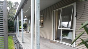 A wooden deck with a stone border, a sliding glass door, and a view of the surrounding garden.