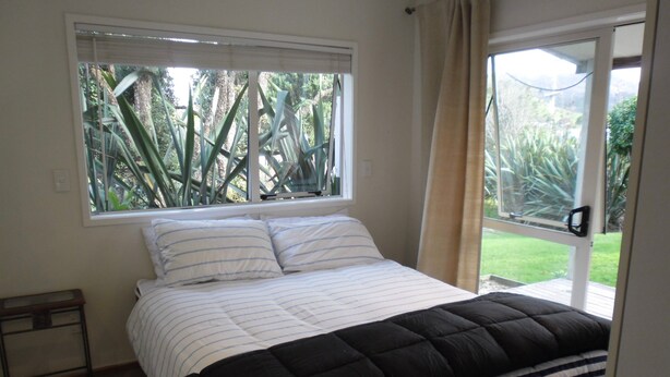 A bedroom with a bed, a window, and a view of greenery outside.