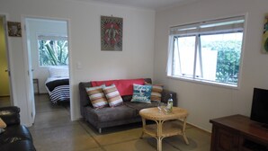 A living room with a sofa, a wicker coffee table, and a television stand.