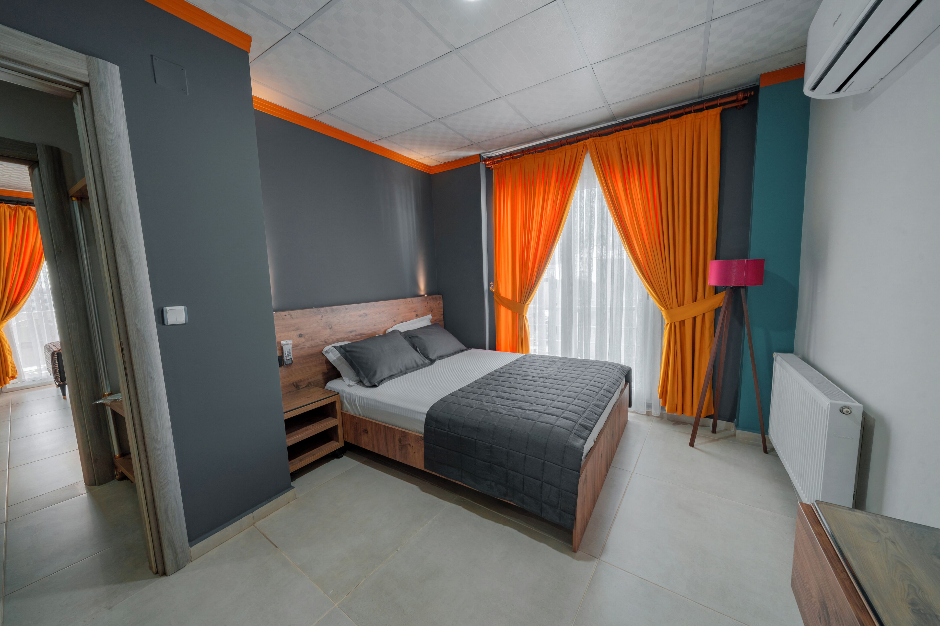 A bedroom with a bed, a nightstand, a lamp, and a radiator.
